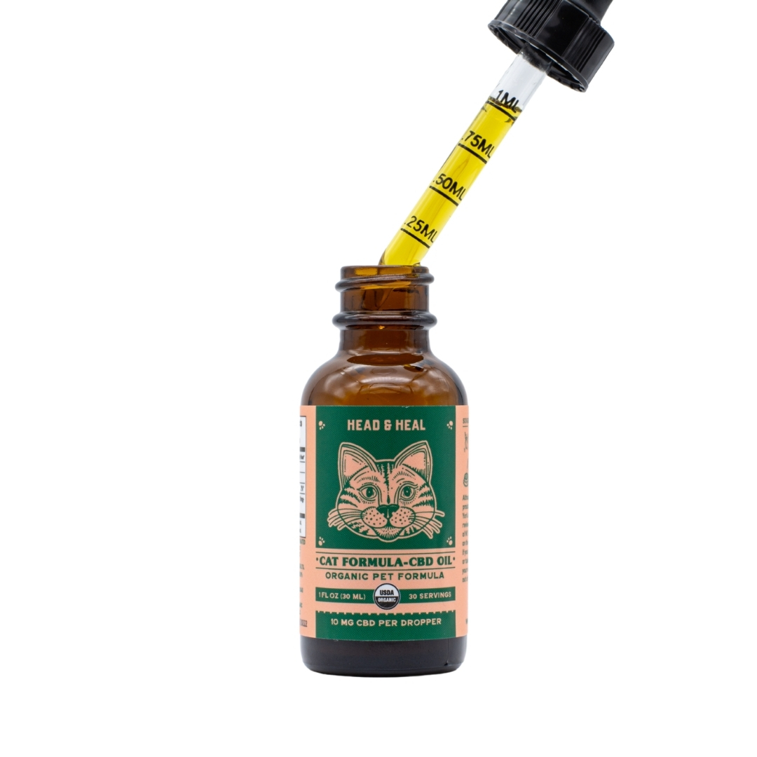 A tincture of Head & Heal Cat Formula CBD Oil on a clear background, with its dropper out to show the color of the oil