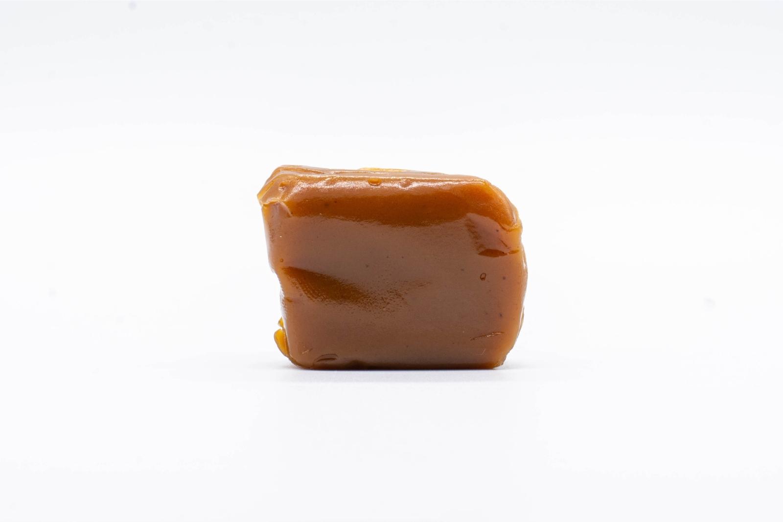 One unwrapped piece of Seventh Hill CBD's CBN Chill caramel, on a clear background