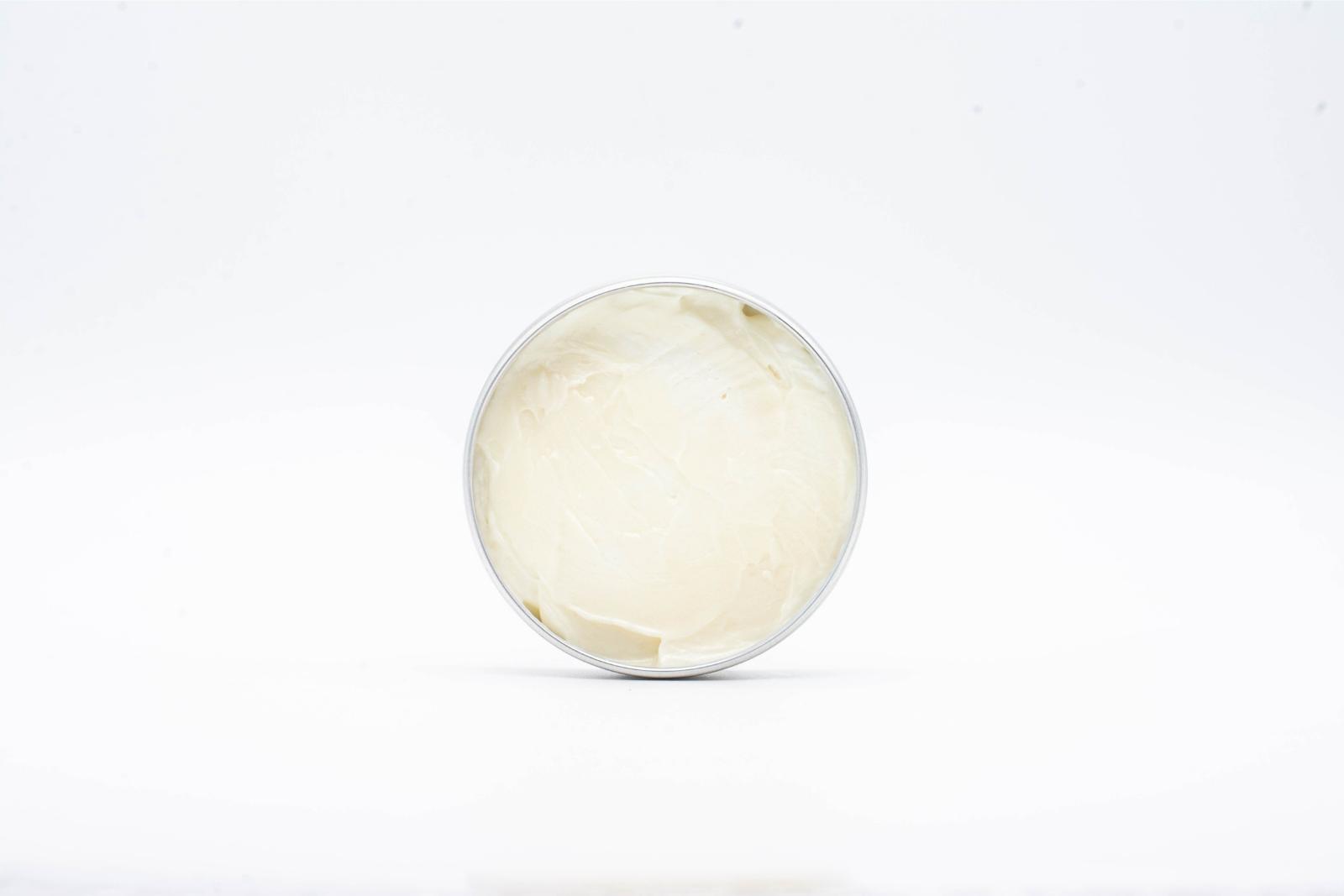 An opened small can to show the color and texture of Tonic's Outer Space CBD + CBG body butter, on a white background