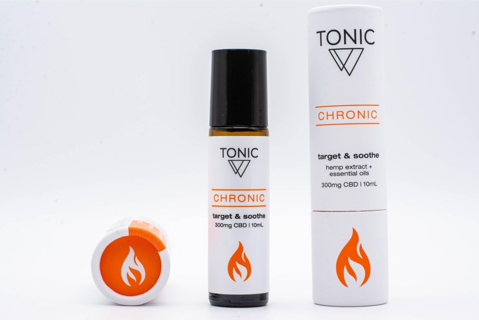 A bottle of Tonic's Chronic CBD + Essential oil roll-on, as well as its container, on a white background