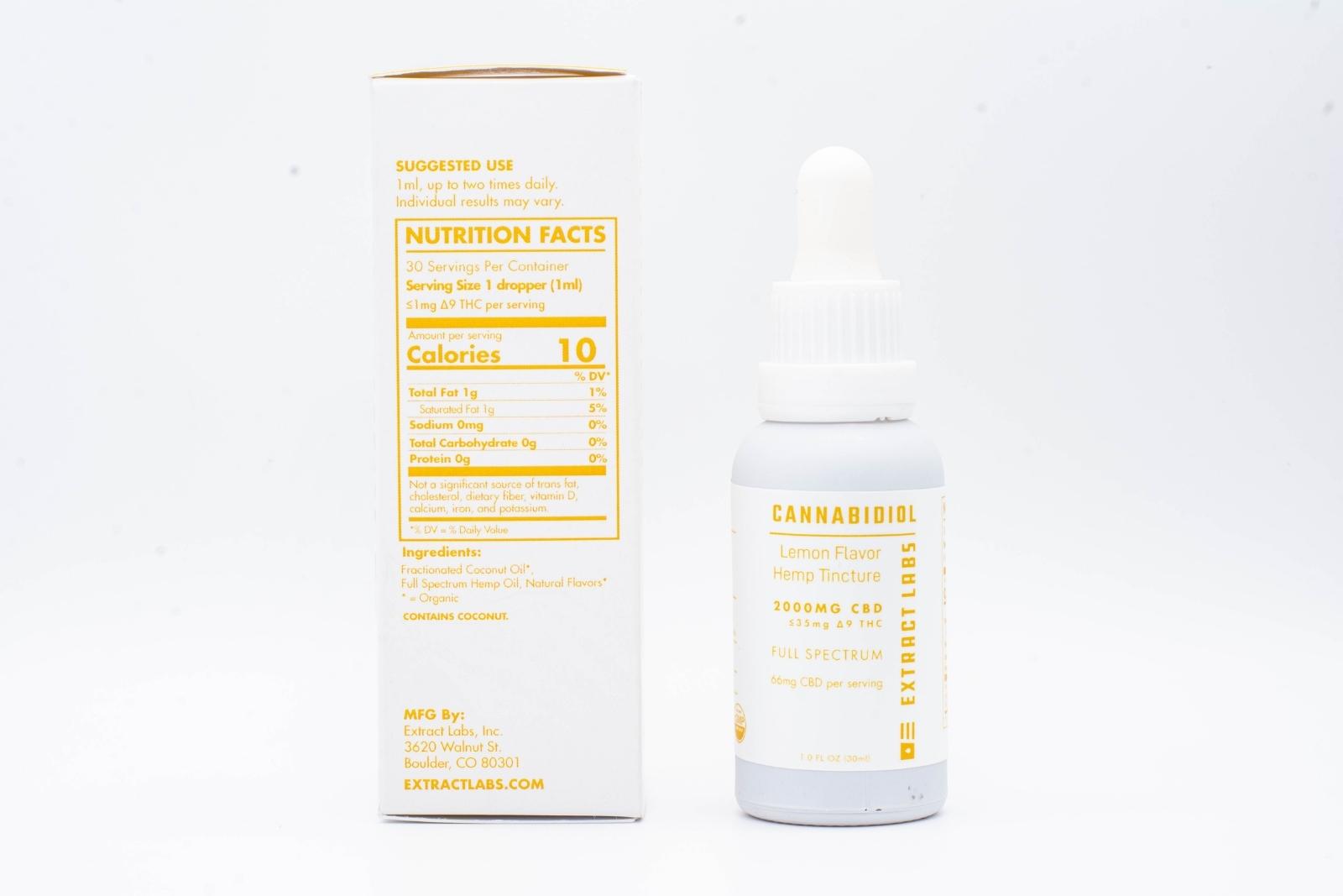 A tincture of Extract Labs Extra Strength Lemon Hemp Extract, next to its packaging, on a white background