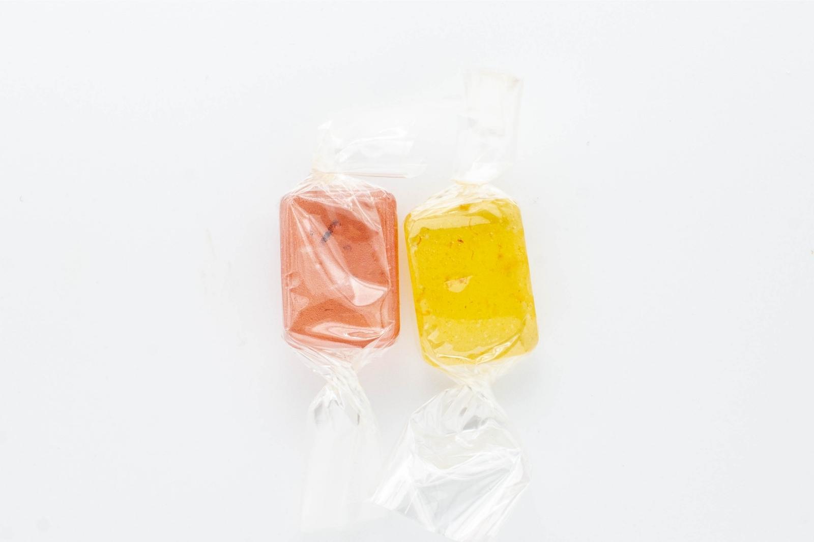 Two varieties of Nice CBD hard candies, raspberry and lemon, on a white background