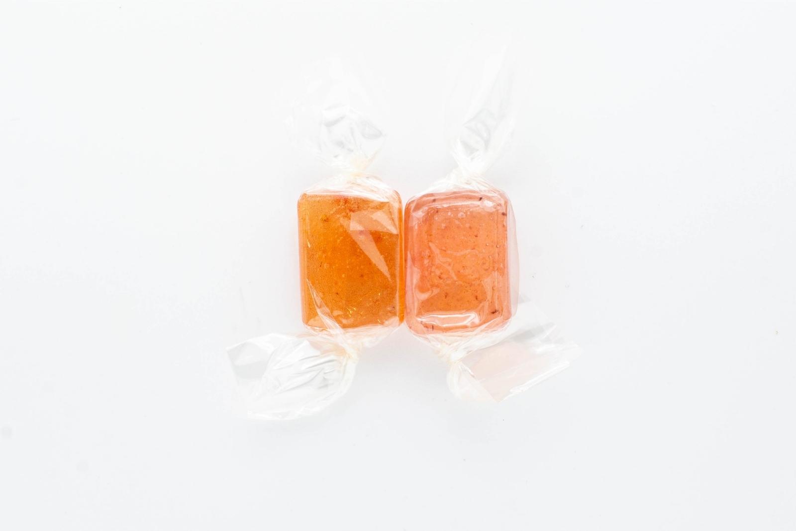 Two varieties of Nice CBD hard candies, strawberry and grape, on a white background