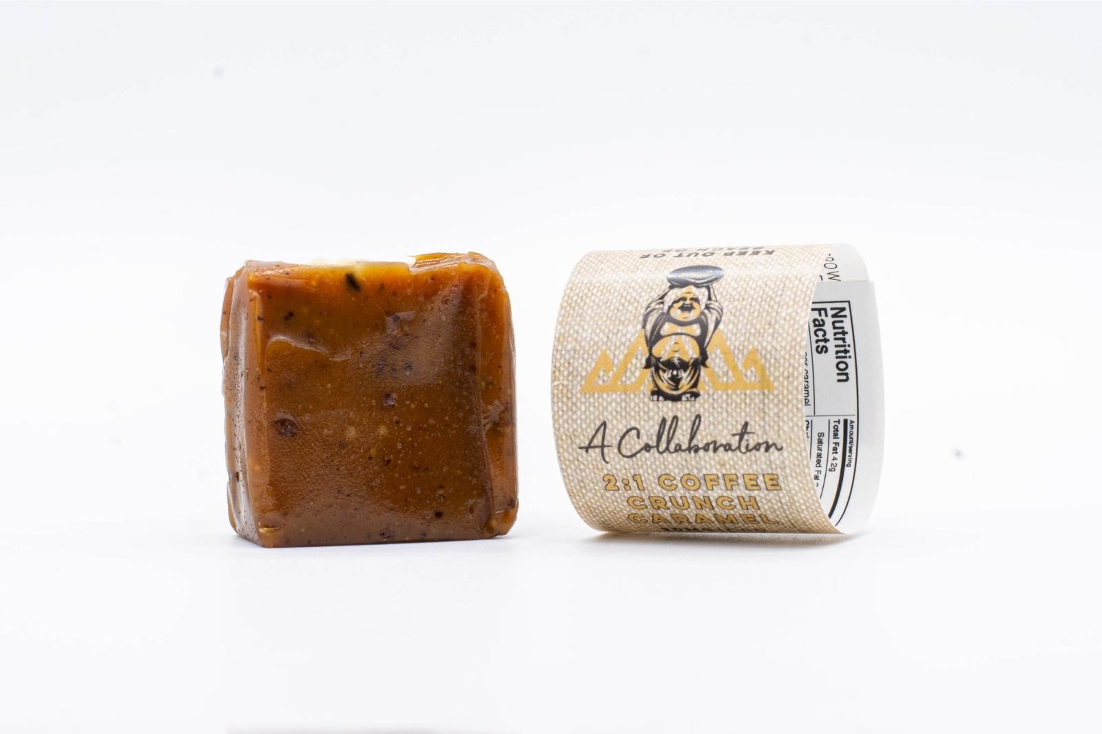 An unwrapped 2:1 Coffee Crunch Caramel by Seventh Hill CBD, next to its sleeve, on a white background