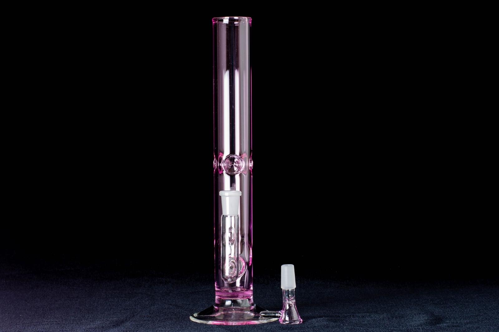 A pink, 12-inch straight tube, made by Jack Glass Co., next to its slide, on a black background