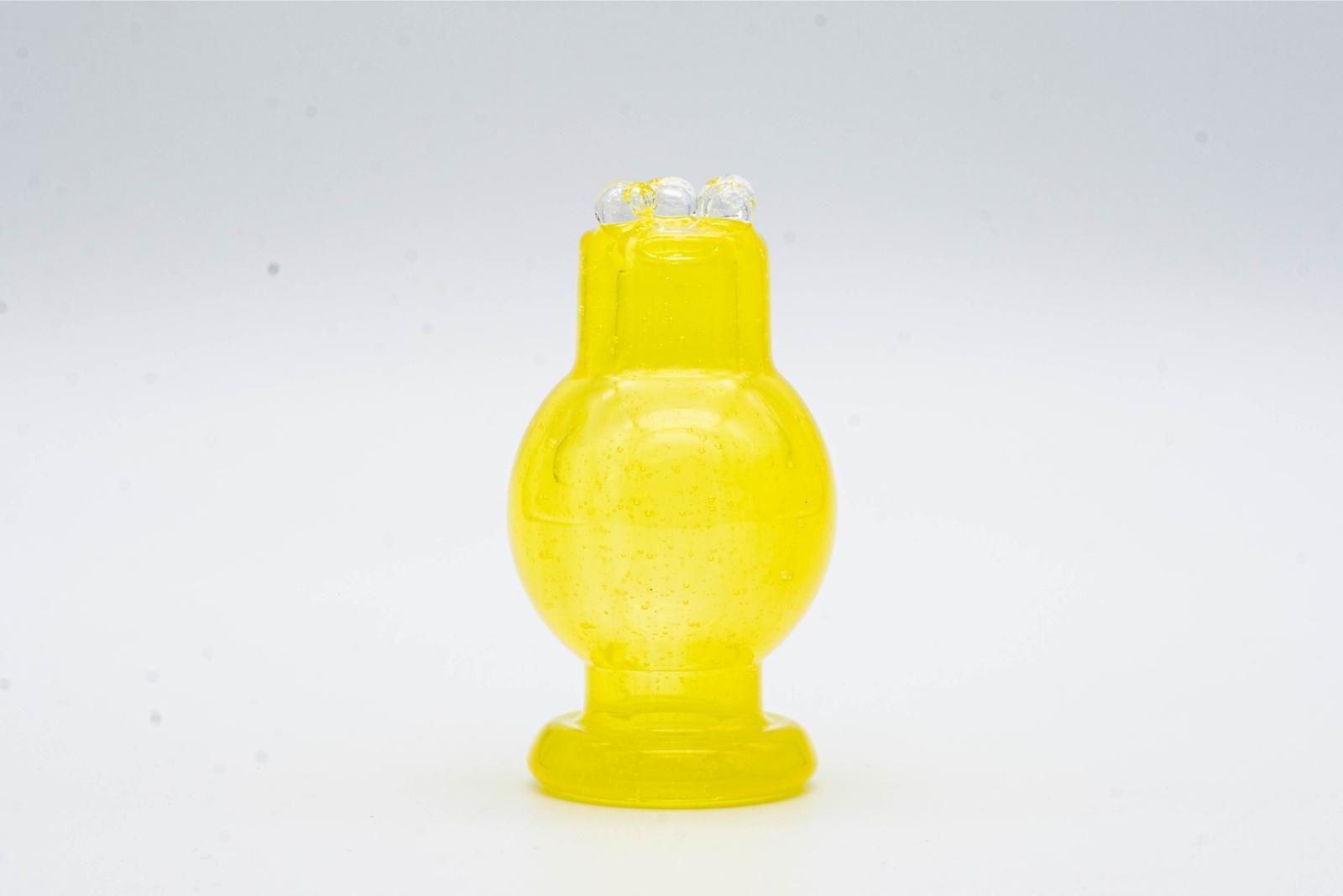 A yellow spinner bubble cap made by BorOregon, on a white background