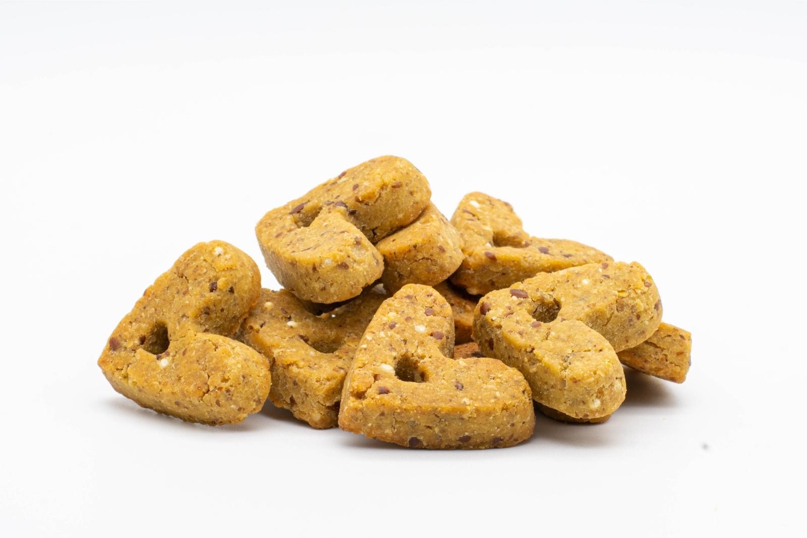 A pile of peanut butter flavored CBD Dog Treats by Head and Heal, on a white background