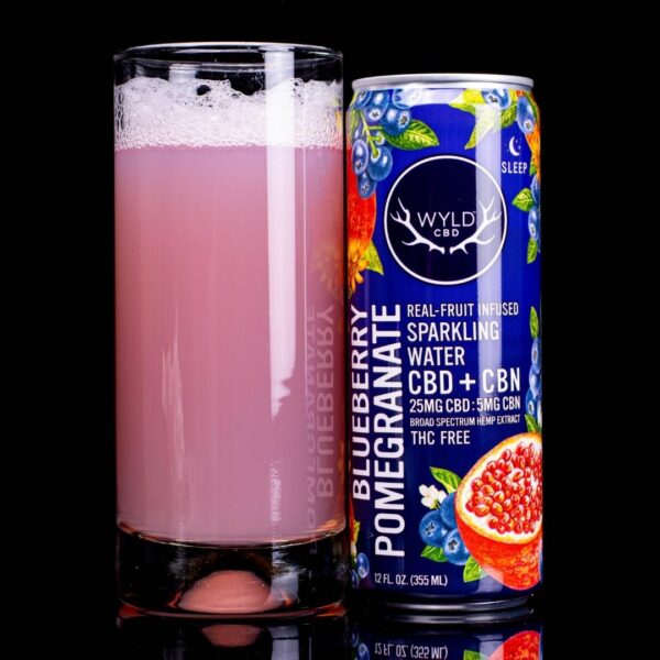 A can of WYLD Blueberry Pomegranate next to a glass with the Blood Orange water poured into it. Both are on a black background