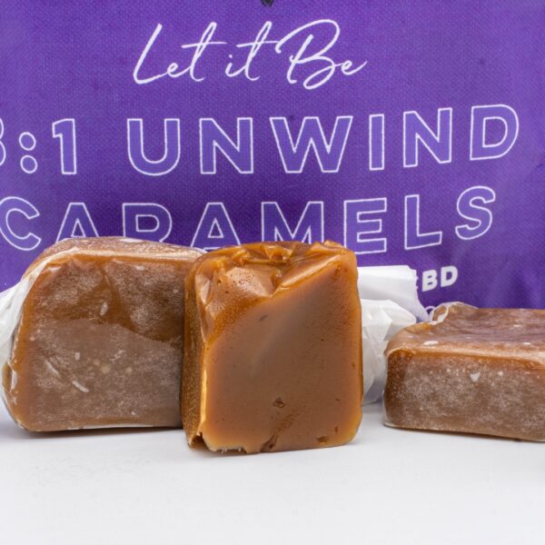A 6 pack, next to a pile of Seventh Hill CBD's 3:1 Unwind Caramel, with one caramel opened, on a white background