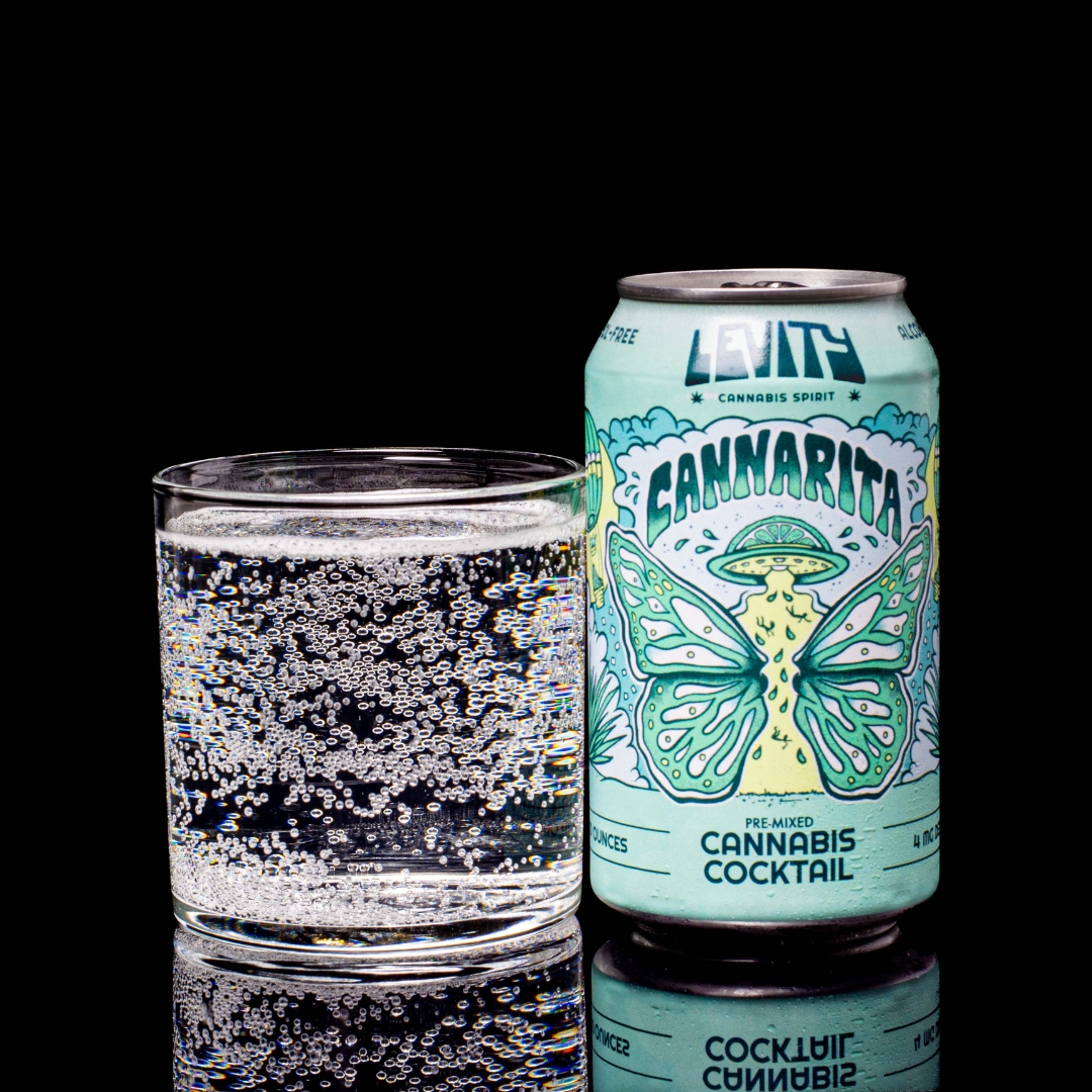 A can of Cannarita flavored Levity Infused Cocktails, next to a glass of Cannarita, on a black background